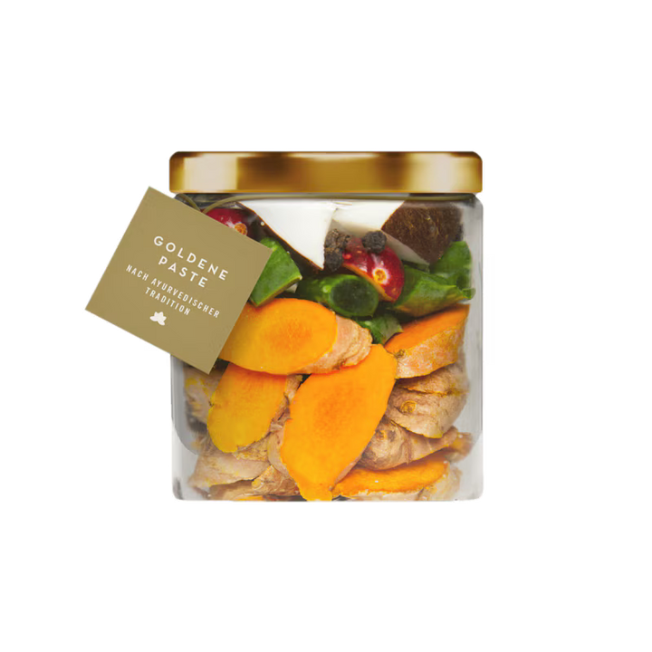Jar of Goldene Paste with a gold lid and visible ingredients on a white background