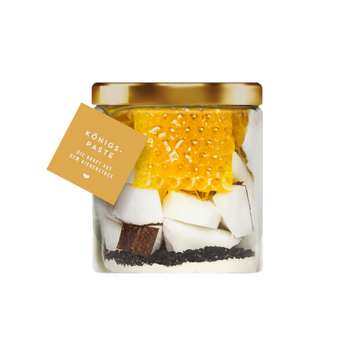 Jar of Königs-Paste with honeycomb and coconut pieces on a white background